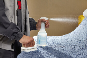 Man using spray to remove stain from carpet in carpet cleaning service