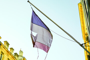 French flag worn faded torn blue white red of france on building