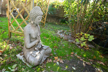 Buddha statue sitting in meditation pose in home garden