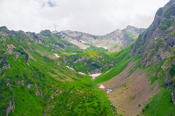 Aerial view of a mountain valley with alpine meadows and streams.