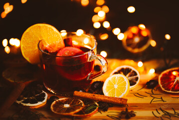 Christmas mulled wine, Drink with dried fruits and berries, Winter hot tea in a glass and spices on a wooden background.