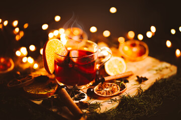 Christmas mulled wine, Drink with dried fruits and berries, Winter hot tea in a glass and spices on a wooden background.
