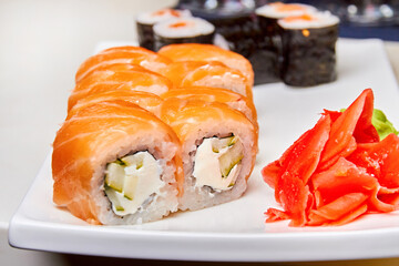 Rolls with salmon and cucumber, cheese and wasabi on a white plate. Closeup, selective focus