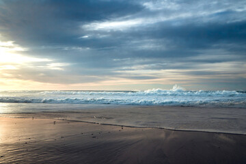 Sunset on the beach. Stormy ocean and beautiful cloudy sky on background
