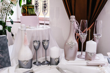 Wedding decor in style of a luxury. Decoration of a photoshoot. Details. Wedding accessories, invitation, box, glasses, bottles champagne, candles on the table. Preparing.