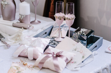 Two glasses of a champagne and pillow with wedding rings. Decoration of a wedding photoshoot. Details of a wedding decor.