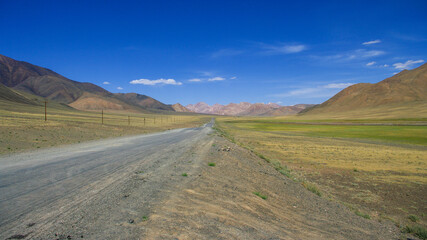 Scenic mountain landscape of long straight stretch of road on high-altitude Pamir Highway near Murghab, Gorno-Badakshan, Tajikistan