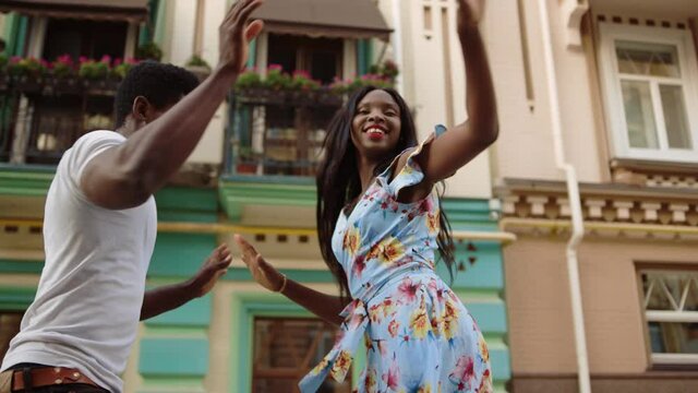 Afro couple dancing on street. African dancers making movements outdoors.