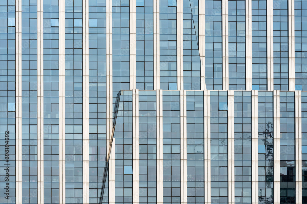 Wall mural a beautiful background of an glass office building, reflecting clouds in the opened windows