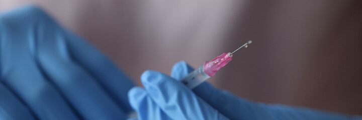 Doctor in gloves holds syringe with a liquid and needle. Medical services in treatment concept