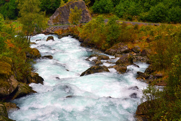 Beautiful waterfall and azure mountain river in the Jostedalsbreen National Park in Norway. Pathway to Briksdal or Briksdalsbreen glacier in Olden. 