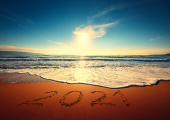 Beautiful sunrise over the sea. Happy New Year 2021 written on seashore.