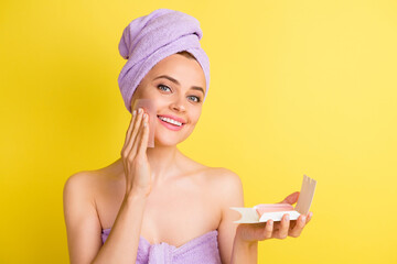 Close-up portrait of charming cheery girl wiping oily skin with napkin isolated over vibrant yellow...