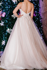 Fototapeta premium Bride in expensive, luxury dress near christmas tree in wedding winter day. Woman, details of models on the collection.