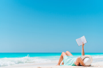 Young woman reading book during tropical white beach
