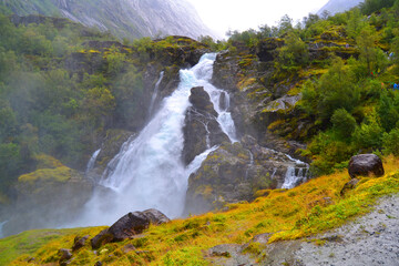 Beautiful waterfall in the Jostedalsbreen National Park in Norway. Pathway to Briksdal or Briksdalsbreen glacier in Olden. 