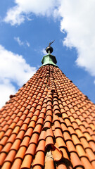 The roof of an ancient church with a cross, shingles