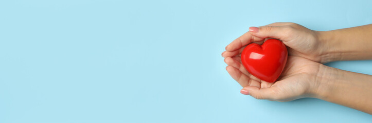 Female hands holding heart on blue background, space for text