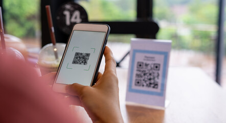 Women's hands are using  the phone to scan the qr code to select food menu. Scan to get discounts...