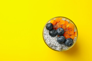 Glass of delicious chia pudding on yellow background