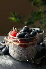 Woman puts blueberry in glass with chia pudding