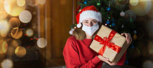 Fototapeta na wymiar girl in red clothes and medical mask unfold New year gifts. the concept of celebrating Christmas midnight. Holiday's decor boce, Christmas tree