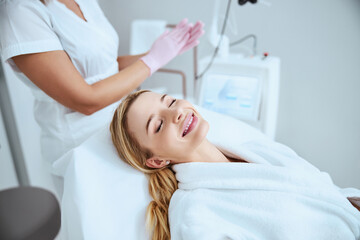 Obraz na płótnie Canvas Pleased blonde female patient in a beauty salon