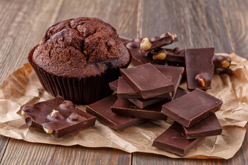 Chocolate cupcake with icing and chocolate bar in Dark lighting,Homemade delicious chocolate muffin on wooden background close-up