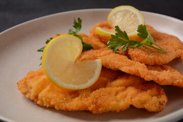 Two chicken breaded schnitzel with lemon on plate