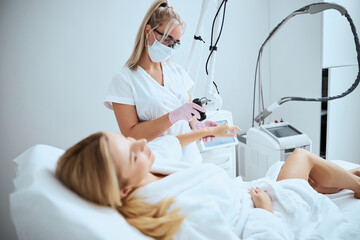 Professional female cosmetologist performing the laser treatment