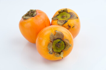 Drei tropische Südfrüchte: Kaki Früchte (lat.: Diospyros kaki) auf einem weißen Hintergrund