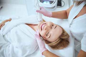 Obraz na płótnie Canvas Young female client enjoying the microneedling procedure