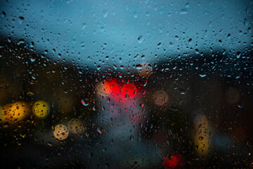 rain drops on the window surface with traffic bokeh light in background 