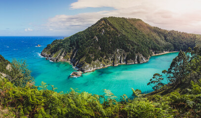 bay of Pechón in Cantabria Spain. Turquoise waters of white sand on a sunny day. Small waves.