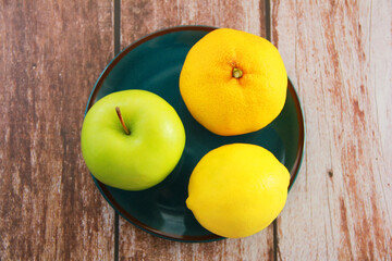 green apple and yellow lemon and tangerine on a decorative plate