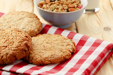 Oat cookies and oat flakes on wooden surface