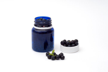 Bottle with vitamin pills, orange, blueberries and mint on white background