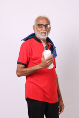 senior indian man drinking fresh water while or after weight training or gym, keeping himself dehydrated