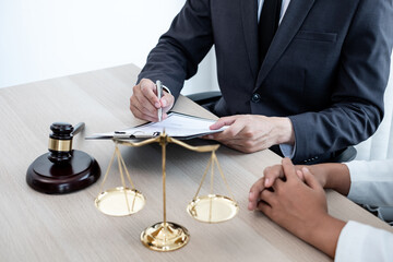 A male lawyer or a judge counseling clients about judicial justice and prosecution with scales, judges gavel, legal documents legal services concept