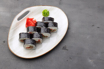 Top view of maki sushi roll on plate on black background