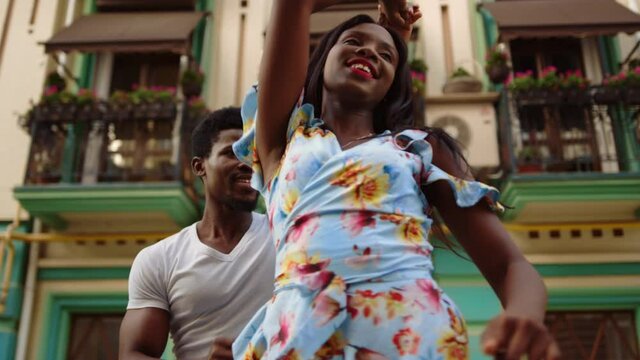 Young afro man and woman dancing bachata on street. Afro couple performing dance