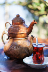 Drinking Traditional Turkish Tea with tea cup and copper tea pot.