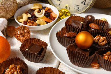 sweet food background for christmas or holiday decoration - chocolate candies, tangerines, nuts and dried fruits on white wood