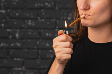 Obraz premium Unrecognizable woman lights cigarette with fire lighter