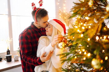 Happy couple decorating christmas tree at home. Smiling Man and Woman together Celebrating Christmas or New Year. Party, family, winter holidays and people concept.