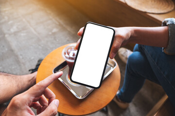 Mockup image of a man pointing finger to a woman while holding and showing white mobile phone with blank desktop screen