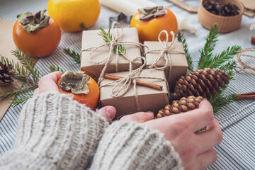 The girl makes a new year composition of gifts Packed with her own hands in Kraft paper, top view, close-up. Happy Christmas background. Preparing for the holiday. Xmas concept