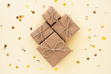 Brown gifts made of Kraft paper on a beige background and confetti, top view, flat lay. Color trend 2021, set sail champagne. Modern gift packaging in natural shades