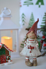 Christmas gnome. Christmas elf. White Christmas lantern with yellow candle light and pillow on background.