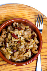 Prawns with garlic and cayenne in a ceramic bowl on a wooden tray